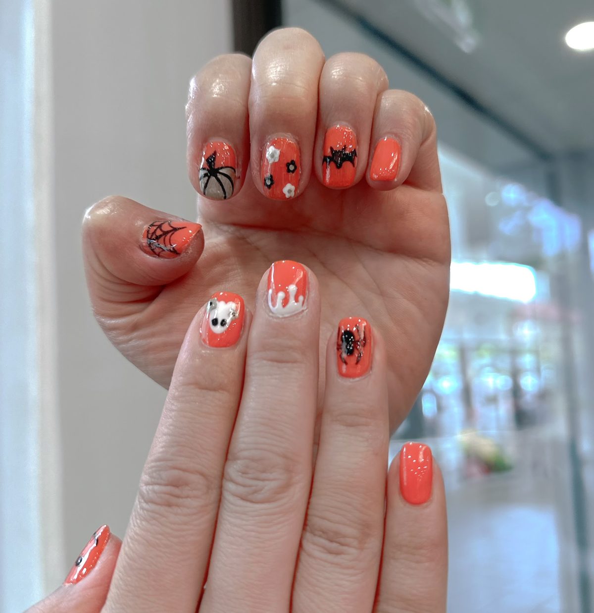 Orange Halloween nail art with pumpkins, bats and a ghost